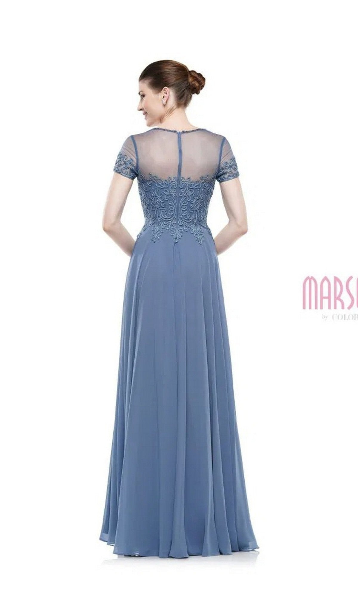 A woman stands facing away from the camera in the Marsoni M271—a long formal dress featuring a chiffon pleated A-line skirt, lace details, and a sheer back.